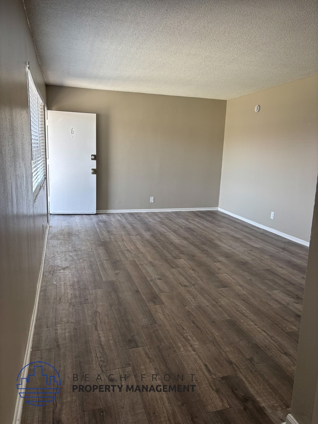 A room with wooden flooring and a white door.